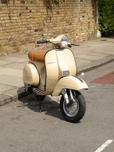 a scooter is parked on the sidewalk next to a brick wall