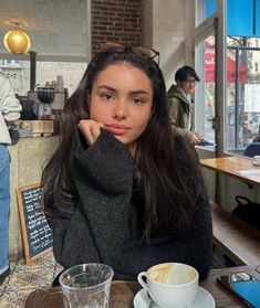 a woman sitting at a table with a cup of coffee