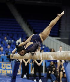 a woman is doing gymnastics on a beam