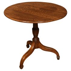 a small round wooden table with wheels on the legs and an oval top, sitting on a white background