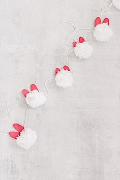 some red and white pom poms are hanging from a string on the wall