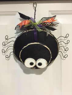 a black hat with googly eyes hanging from a hook on a white door frame