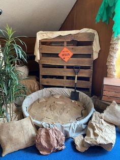 an old wooden crate with sand in it and some plants on the ground next to it