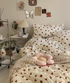 a bed with hearts on it in a bedroom next to a lamp and pictures hanging on the wall