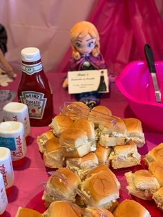 sandwiches and condiments on a pink tablecloth at a children's birthday party