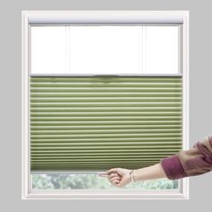 a woman standing in front of a window with green blinds