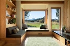 a window seat in the corner of a room with open bookshelves and windows