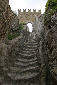 the stairs lead up to an old stone castle