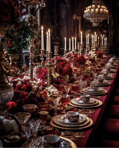 a long table is set with red flowers and silverware for a formal dinner party