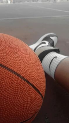 an orange basketball sitting on the ground next to a person's feet