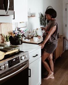 a woman is standing in the kitchen with her feet on the counter and holding a coffee pot