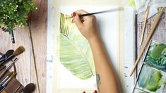 a person is drawing on a piece of paper with watercolors and paintbrushes