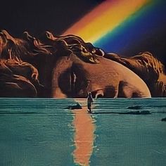 a person standing in the water with their head on his back and rainbow reflected in the water