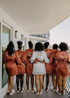 a group of women in orange robes standing on a balcony looking out at the ocean