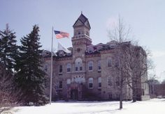 an old building in the middle of winter with snow on the ground and trees around it