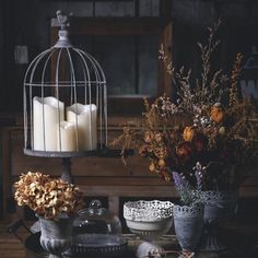 a birdcage filled with candles sitting on top of a table next to flowers