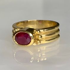 A simple and elegant vintage east/ west ring featuring a candy colored oval shaped ruby weighing 1.15 carats set in solid 14k yellow gold with a bezel setting which elevates the stone above the finger. *Ring size: 6 1/2 *Ring weight: 5.21 grams *Complimentary resizing is available up to 3 sizes larger or smaller than stated size. Classic Oval Gemstone Ring, Modern Gold Oval Ruby Ring, Modern Oval Ruby Ring In Gold, Modern Oval Gold Ruby Ring, Classic Oval Hallmarked Emerald Ring, Classic Oval Emerald Ring Hallmarked, Oval Ruby Signet Ring For Anniversary, Classic Oval Emerald Ring, Classic Ruby Ring Oval Cabochon For Formal Occasions