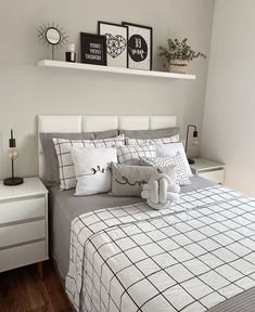 a bed with white sheets and black and white pillows on top of it, along with two framed pictures above the headboard