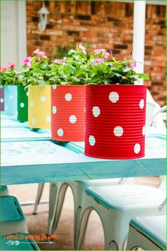 three colorful flower pots sitting on top of a blue table