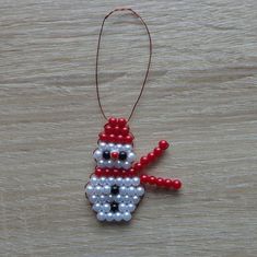 a beaded snowman ornament hanging on a wooden table