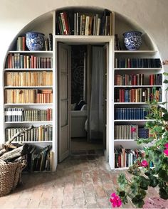 an arched doorway leads to a well - lit room with bookshelves full of books