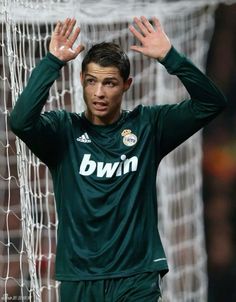 a soccer player holding his hands up to his head while standing in front of the net