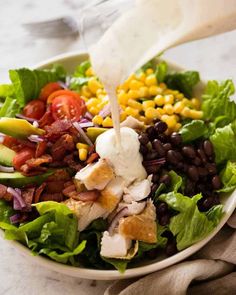 a salad with dressing being poured into it