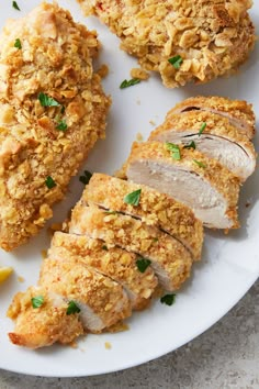 sliced chicken on a white plate with lemon wedges and parmesan crumbs