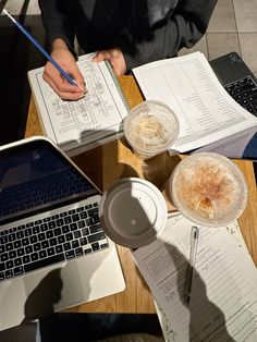 a person sitting at a table with two laptops and papers on top of it