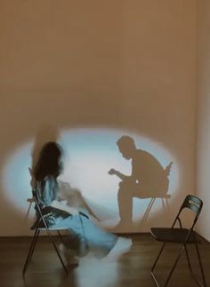 a person sitting in a chair next to a projected image of a man and woman