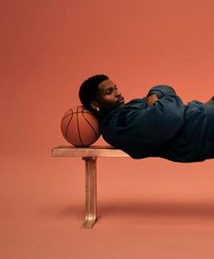 a man laying on top of a bench next to a basketball