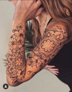 a woman holding her hand to her face with flowers tattooed on the arm and shoulder