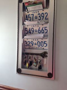 a mirror hanging on the wall displaying license plates and keychain holders with keys in them