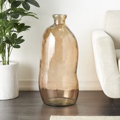 a vase sitting on the floor next to a potted plant