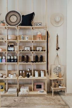 a room filled with lots of different items on wooden shelving next to a chair