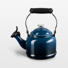 a blue tea kettle with a black handle on the top and bottom, in front of a white background