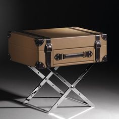 a brown suitcase sitting on top of a metal stand