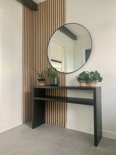 a mirror sitting on top of a wooden table next to a potted plant in front of it