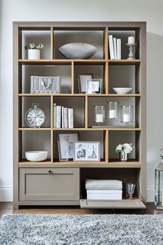 a living room filled with lots of bookshelves next to a white rug on top of a hard wood floor