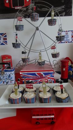 cupcakes are on a tray in front of a ferris wheel and british flags