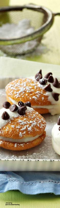 three cookies with chocolate chips and cream on top are sitting on a plate next to a colander