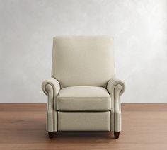 a beige chair sitting on top of a hard wood floor next to a white wall