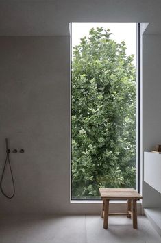 a bathroom with a large window and a bench in front of the shower area is shown