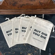 four burlied bags with words on them sitting on a marble counter top next to a clock