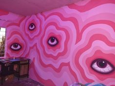 a room with pink walls and large eyes painted on the wall