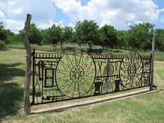 an iron gate with wheels on it in the middle of a field