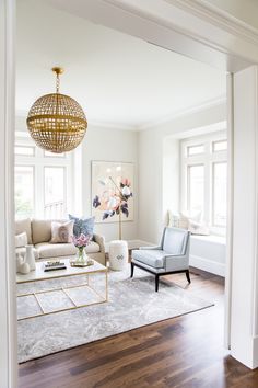 a living room filled with furniture and a chandelier hanging over the top of it