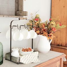 a table topped with plates and vases filled with flowers next to a wooden cabinet