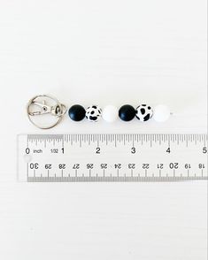 three black and white balls are on a measuring tape, with one bead in the middle