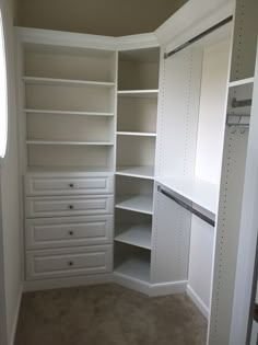 an empty walk in closet with white shelves and drawers